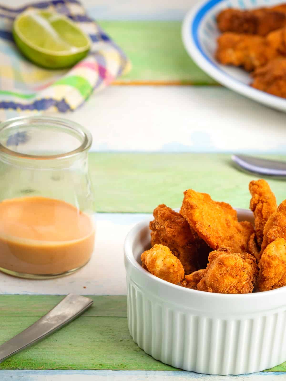 Fish Sticks with Sweet Mayo Fish sticks in a white ramekin on green and white wooden background.