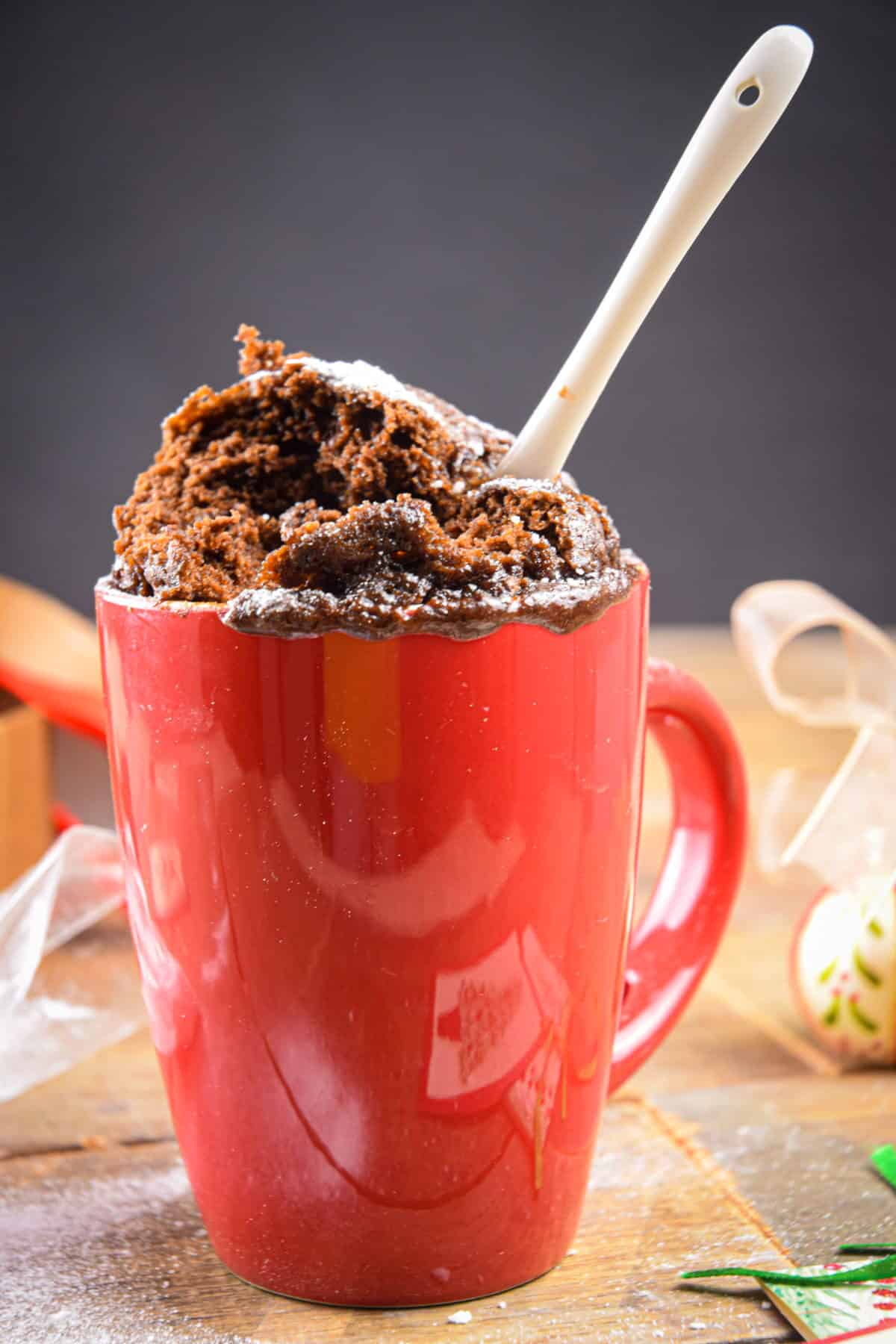Chocolate mug cake prepared in a red mug with a white spoon.
