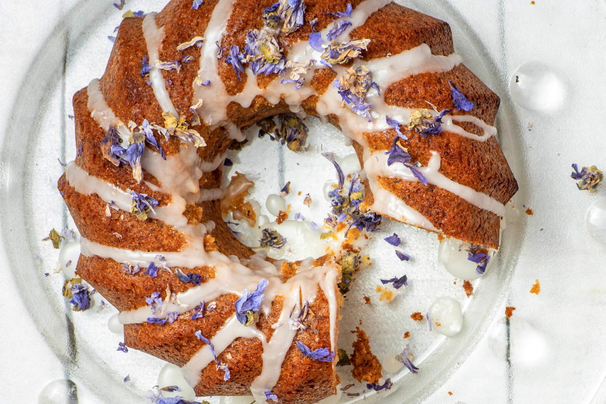 Grapefruit Vanilla Cake with lavender on clear glass plate and white background.