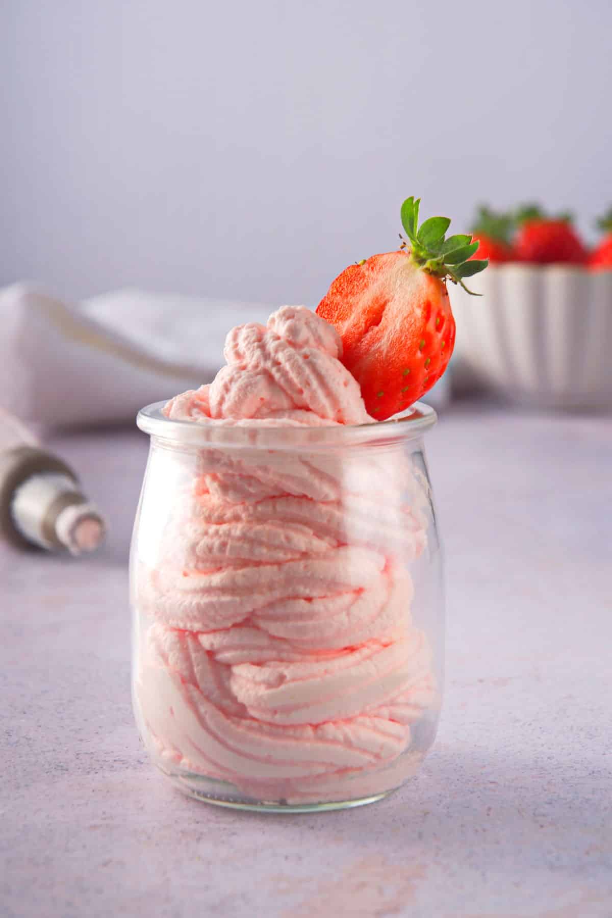 Pink grenadine whipped cream in glass jar with fresh strawberries.