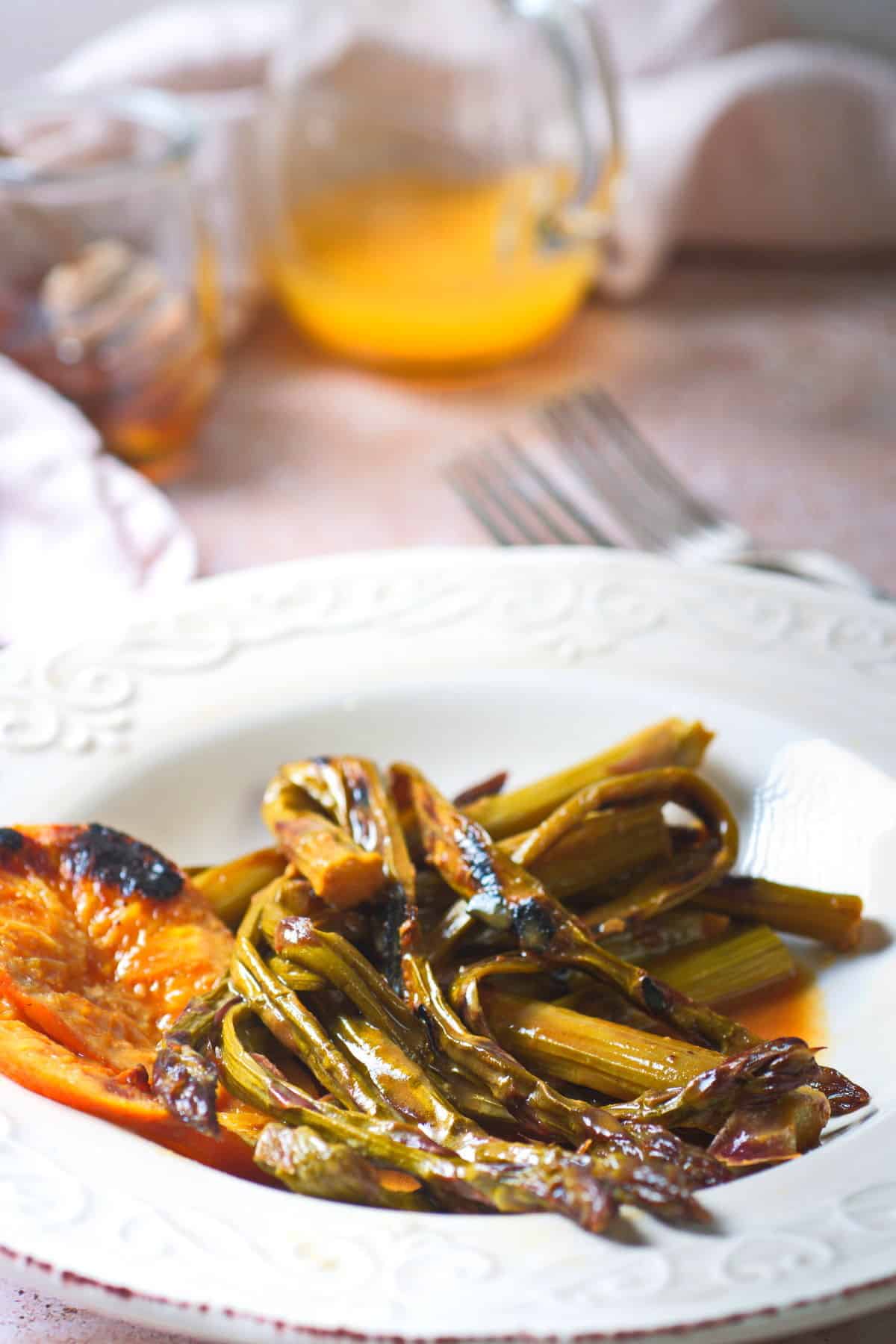 Grilled asparagus and orange slices on white plate.