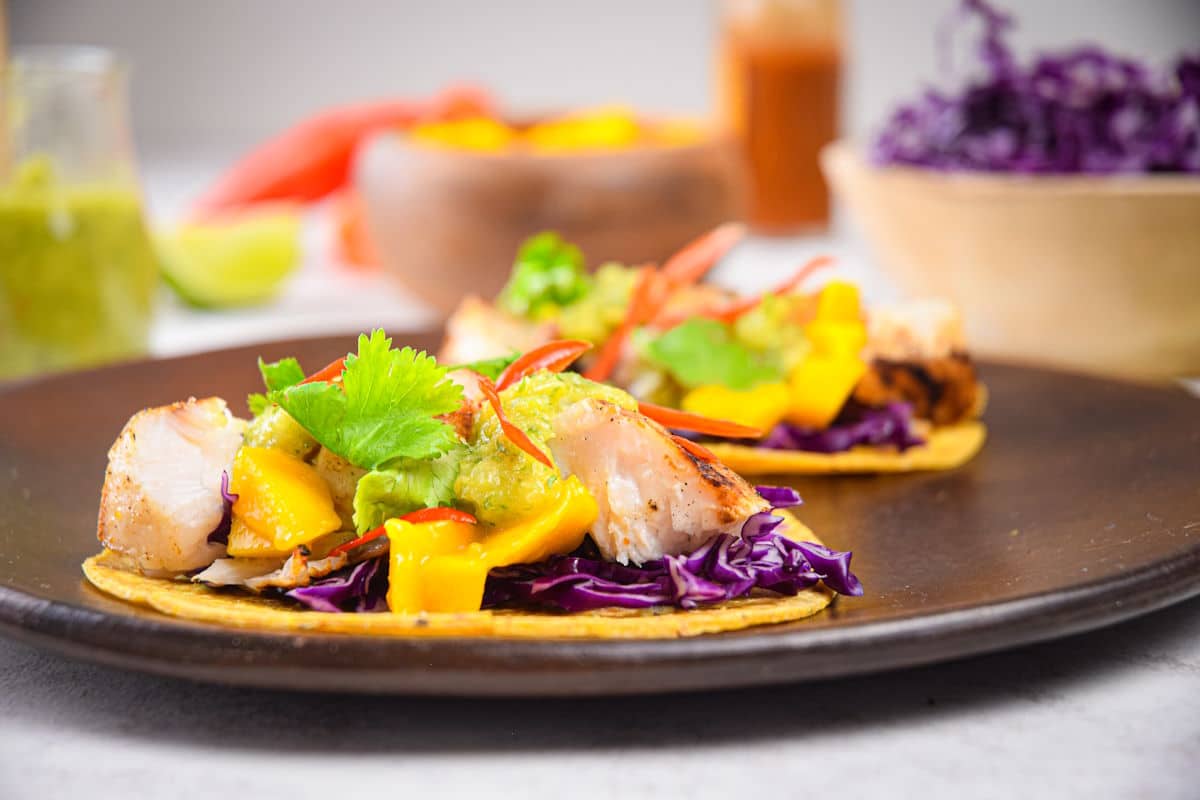 Halibut tacos with salsa, mango and fresh veggies on plate.