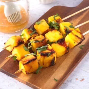 Grilled cubed mango on wooden skewers.