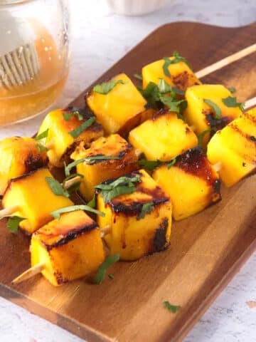 Grilled cubed mango on wooden skewers.