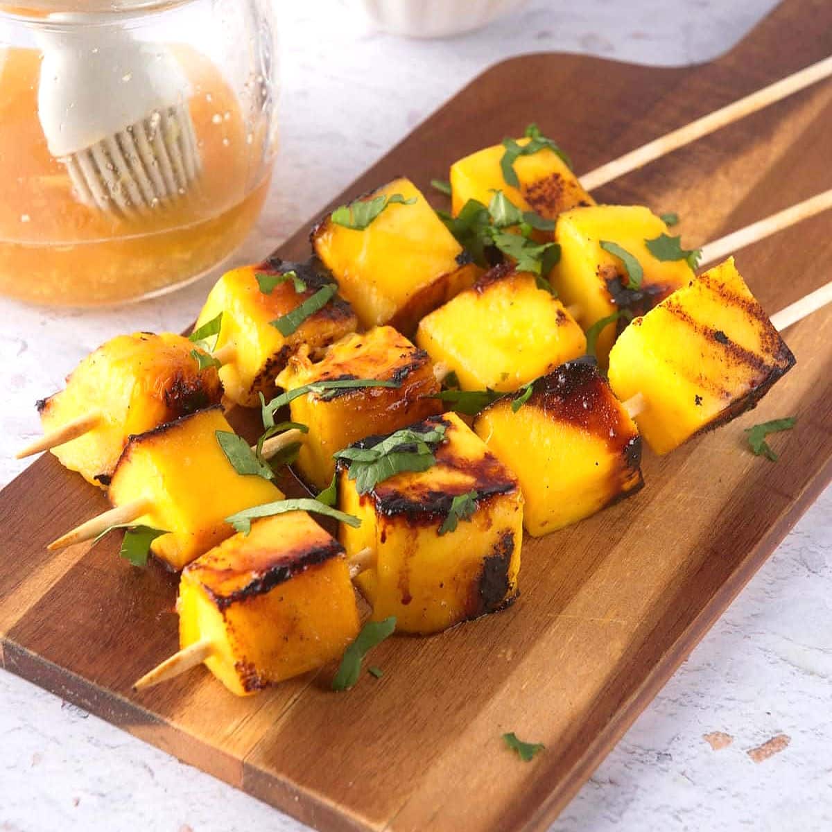 Grilled cubed mango on wooden skewers.