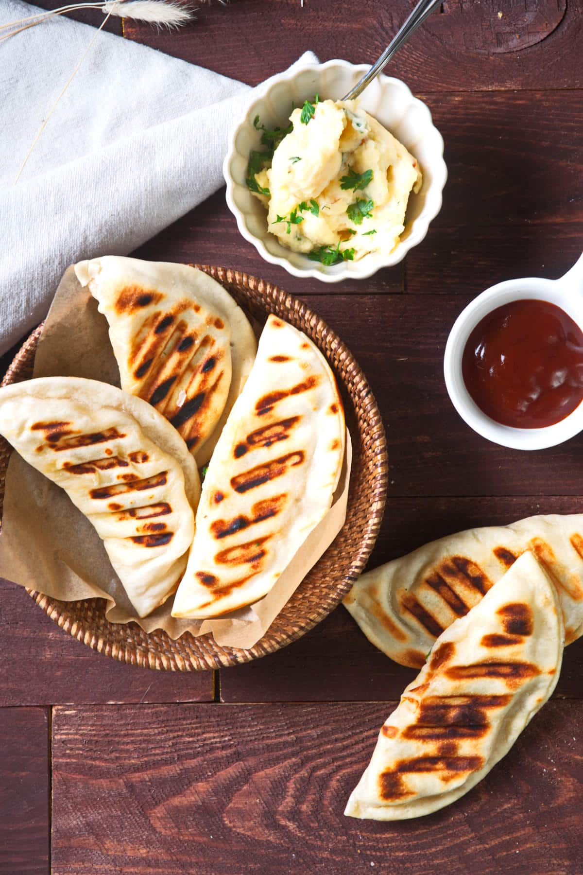 Grilled pierogies in basket with BBQ sauce on the side.
