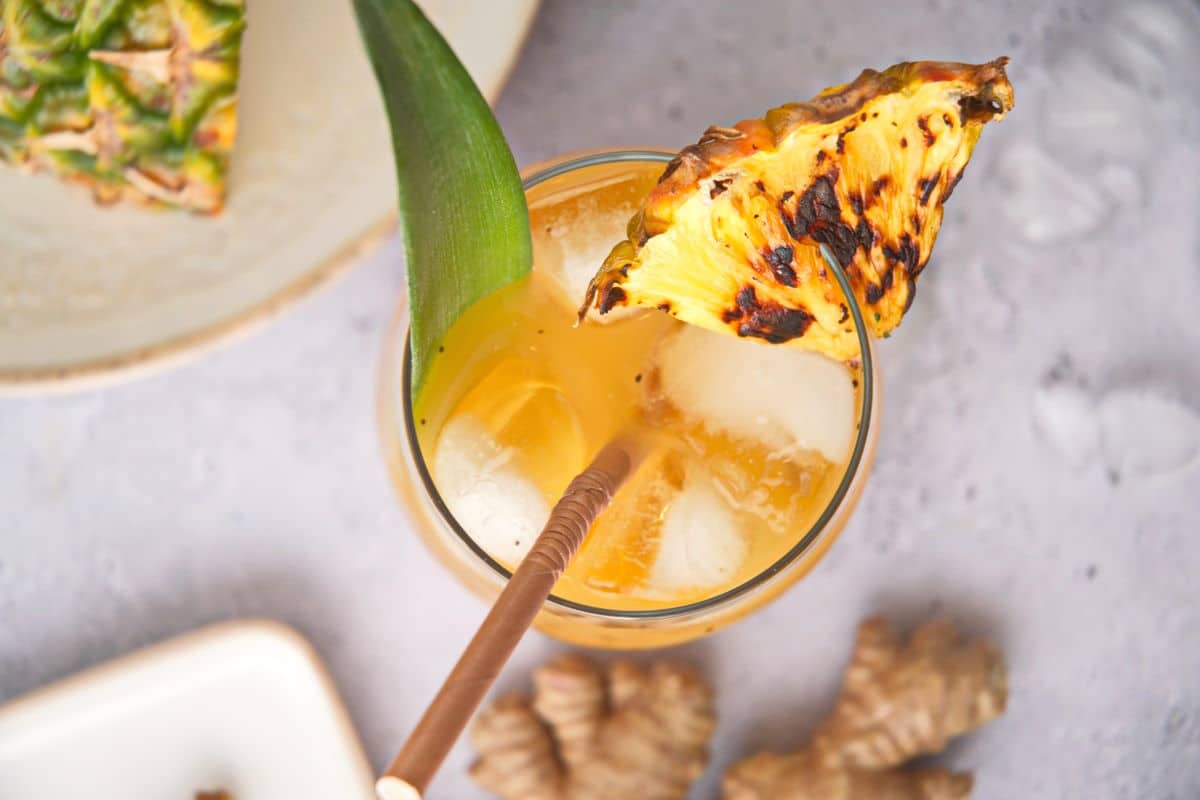 Grilled pineapple juice and wedge in stemless wine glass.