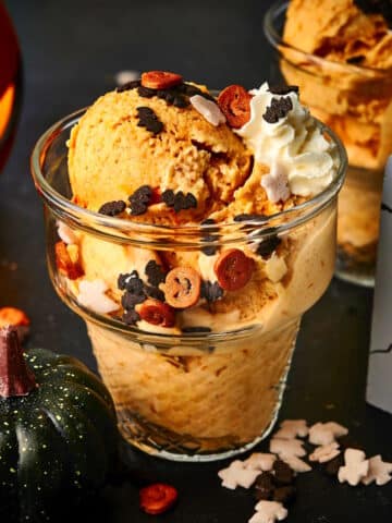 Halloween ice cream in glass ice cream dish with spooky candies and decor.