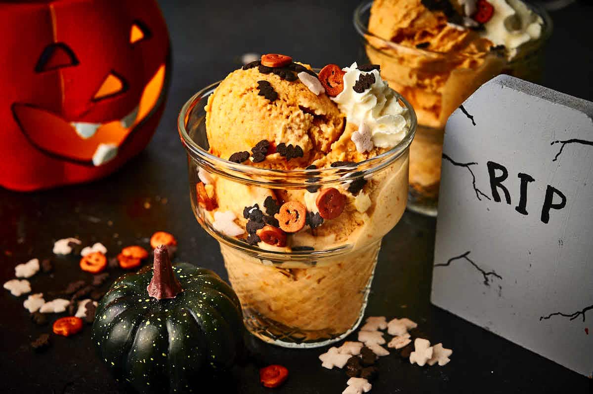 Halloween ice cream on black background with RIP sign and glowing pumpkin.