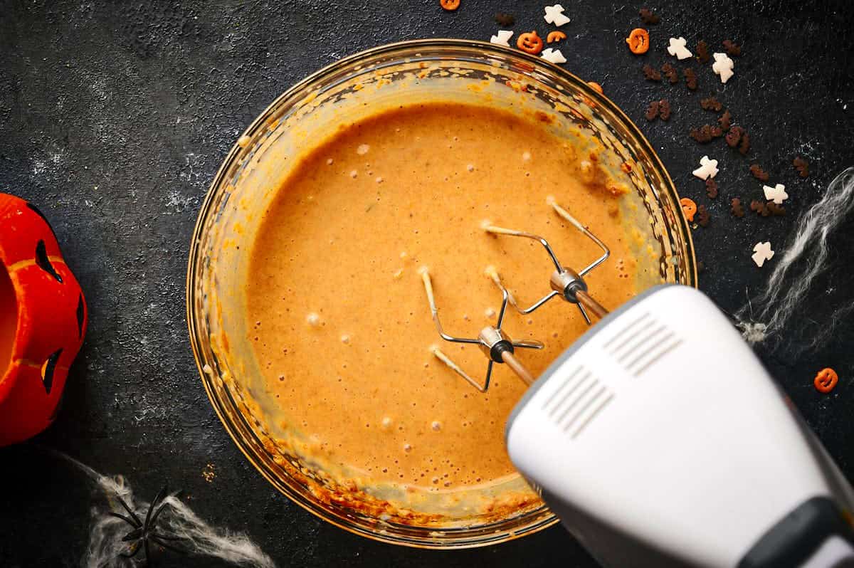 Pumpkin mixture in bowl with electric hand mixer.
