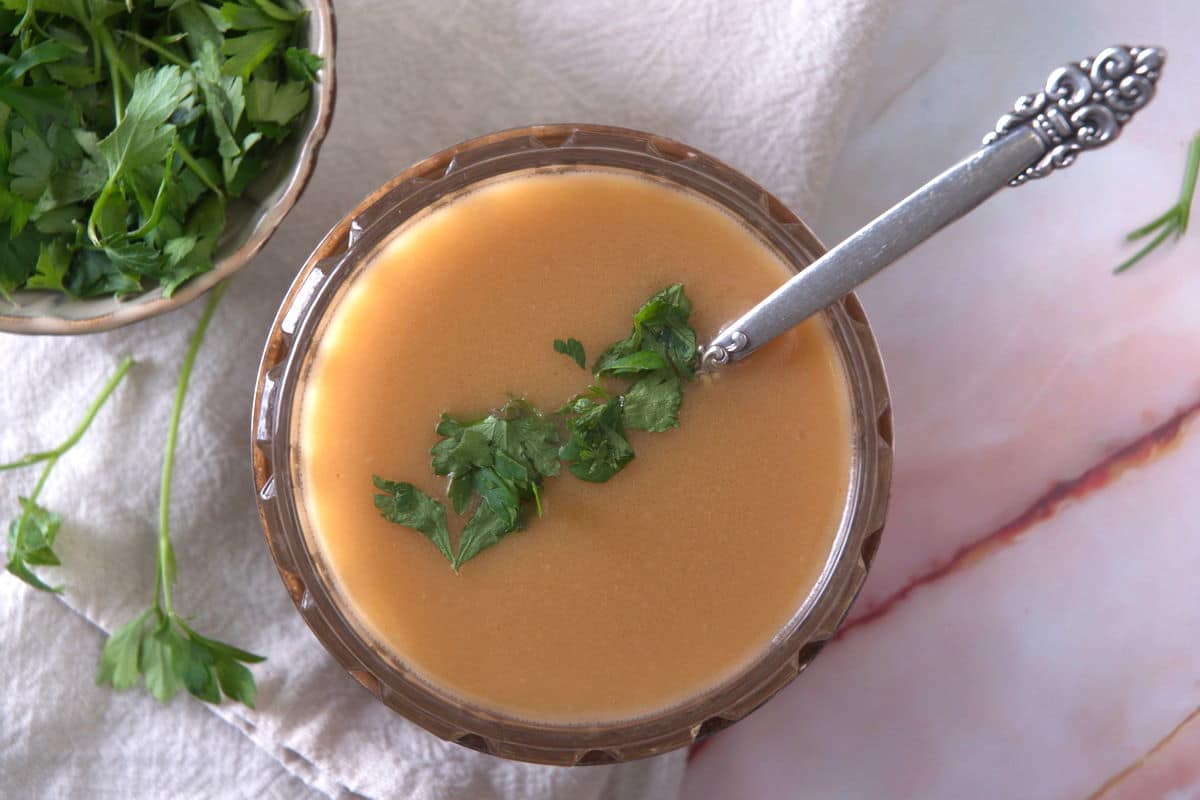 Ham gravy in a bowl with freshly chopped parsley.