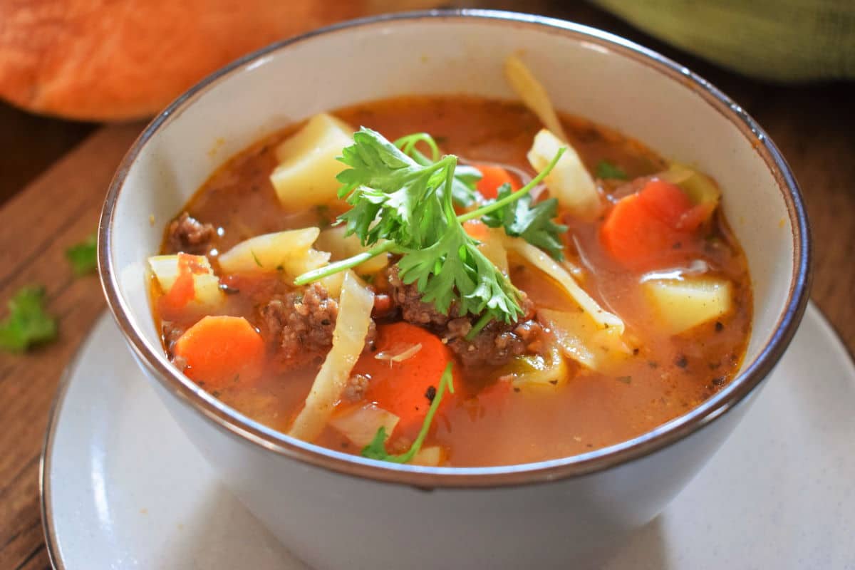 Beef and cabbage soup in a blue bowl.