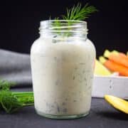 Ranch dressing in small jar on black background.