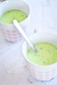 Vegan matcha latte in 2 white mugs with pink polka dots.