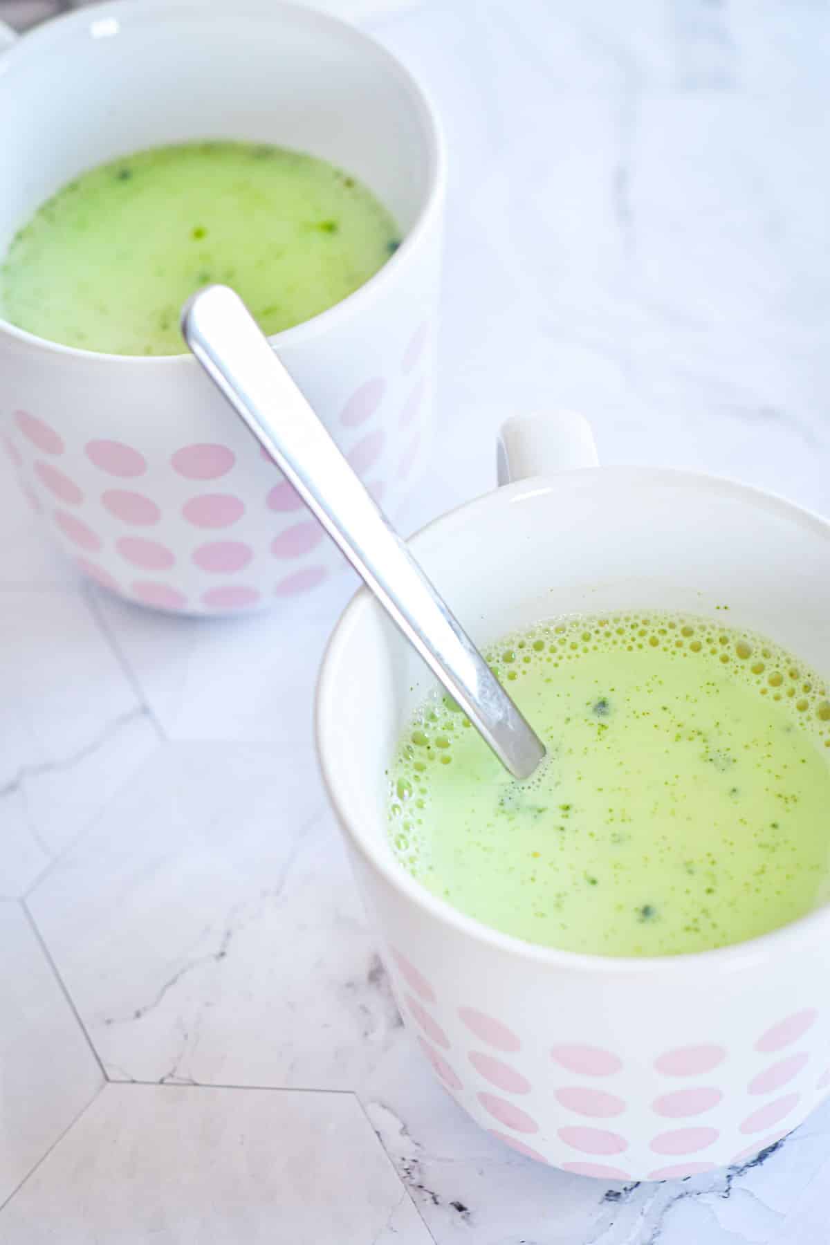 Vegan matcha latte in 2 white mugs with pink polka dots.