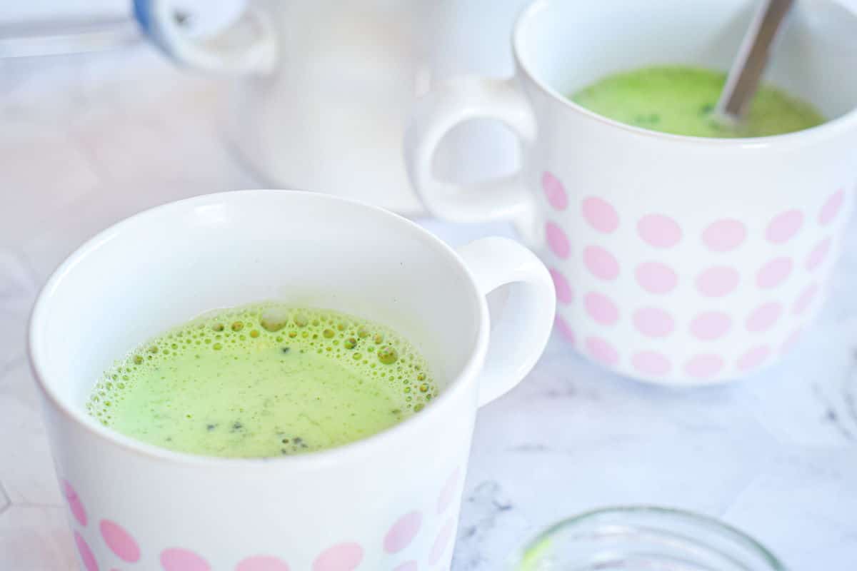 Vegan matcha latte in 2 white mugs with pink polka dots.