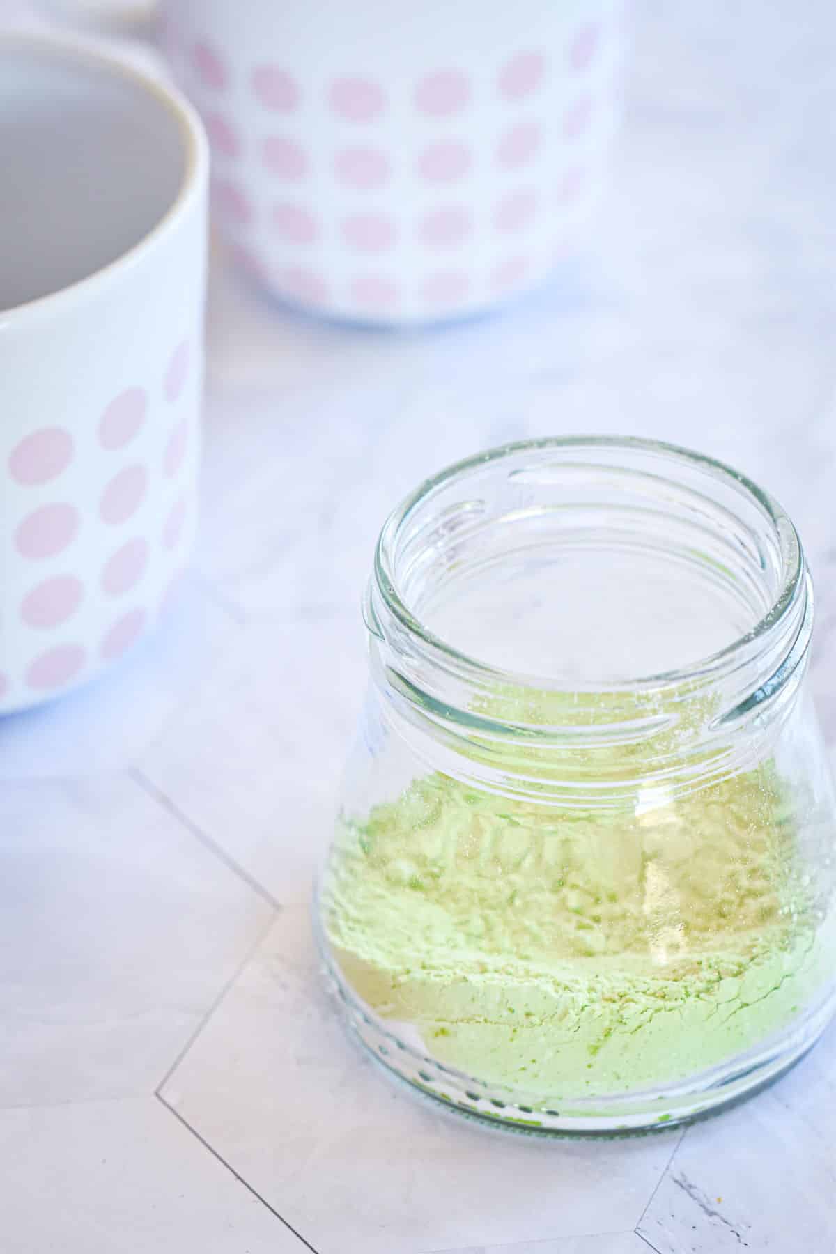 Vegan matcha latte powder in small jar.