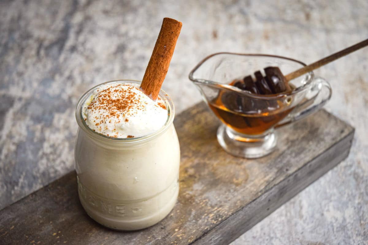 Whipped topping in a bowl with cinnamon and honey in a separate bowl.