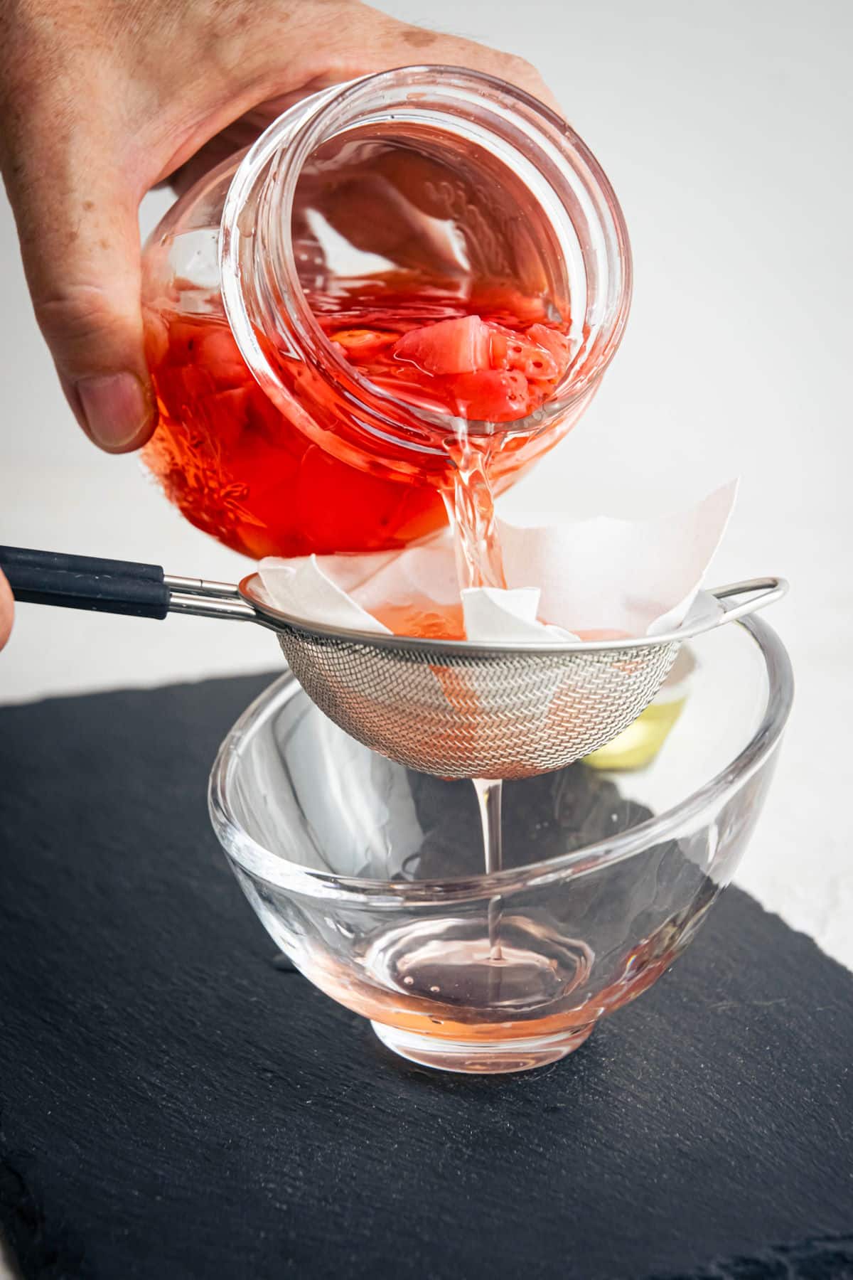Cheese cloth and strainer with strawberry liqueur running through it.