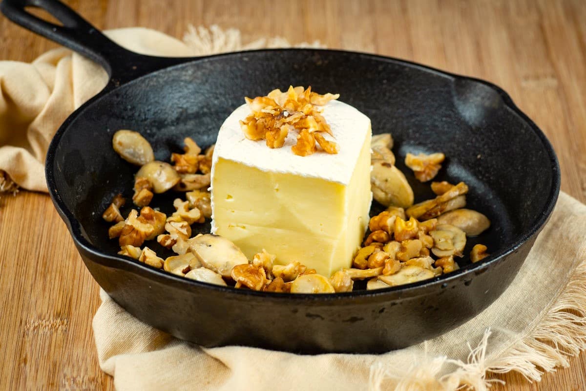 Brie wedge in cast iron pan with walnuts and mushrooms.