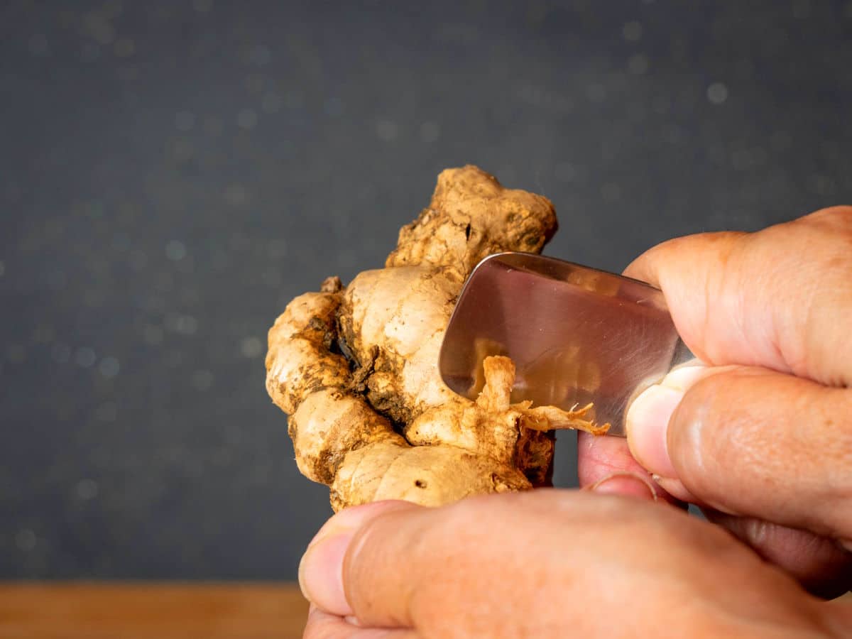 Ginger root in hands with a spoon.