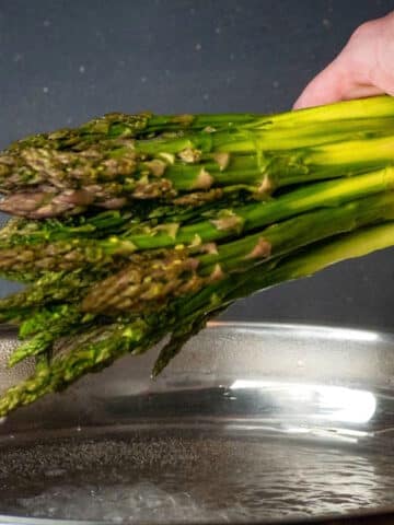 Bunch of fresh asparagus over pan.