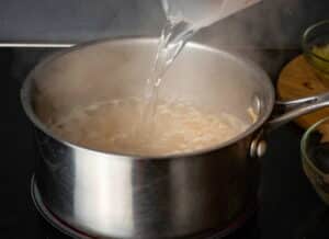 Pot on stove with hot water and brown rice.