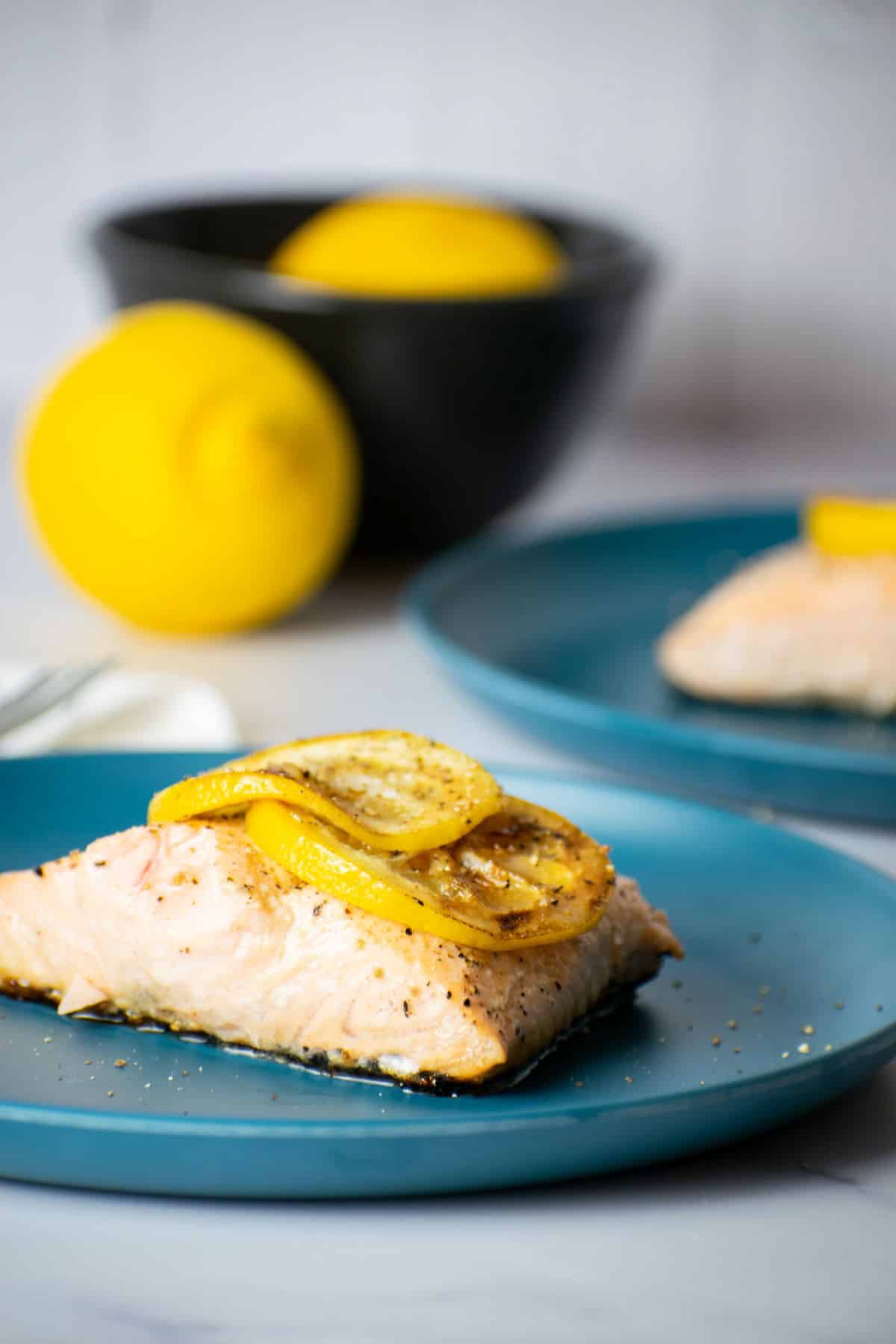 How to Cook Salmon With Skin Step 8-6 Cooked salmon fillet with lemon slices on blue plate.