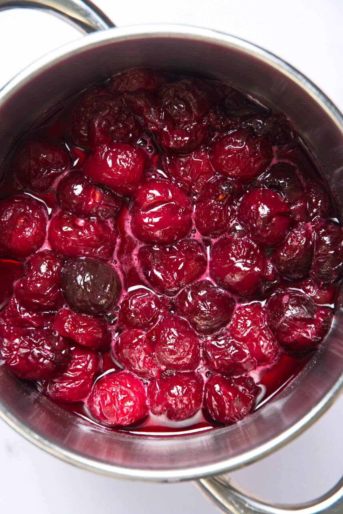 Cherries in a sugar syrup cooling in saucepan.