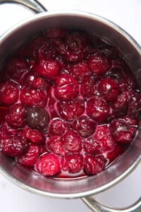 Cherries in a sugar syrup in saucepan.
