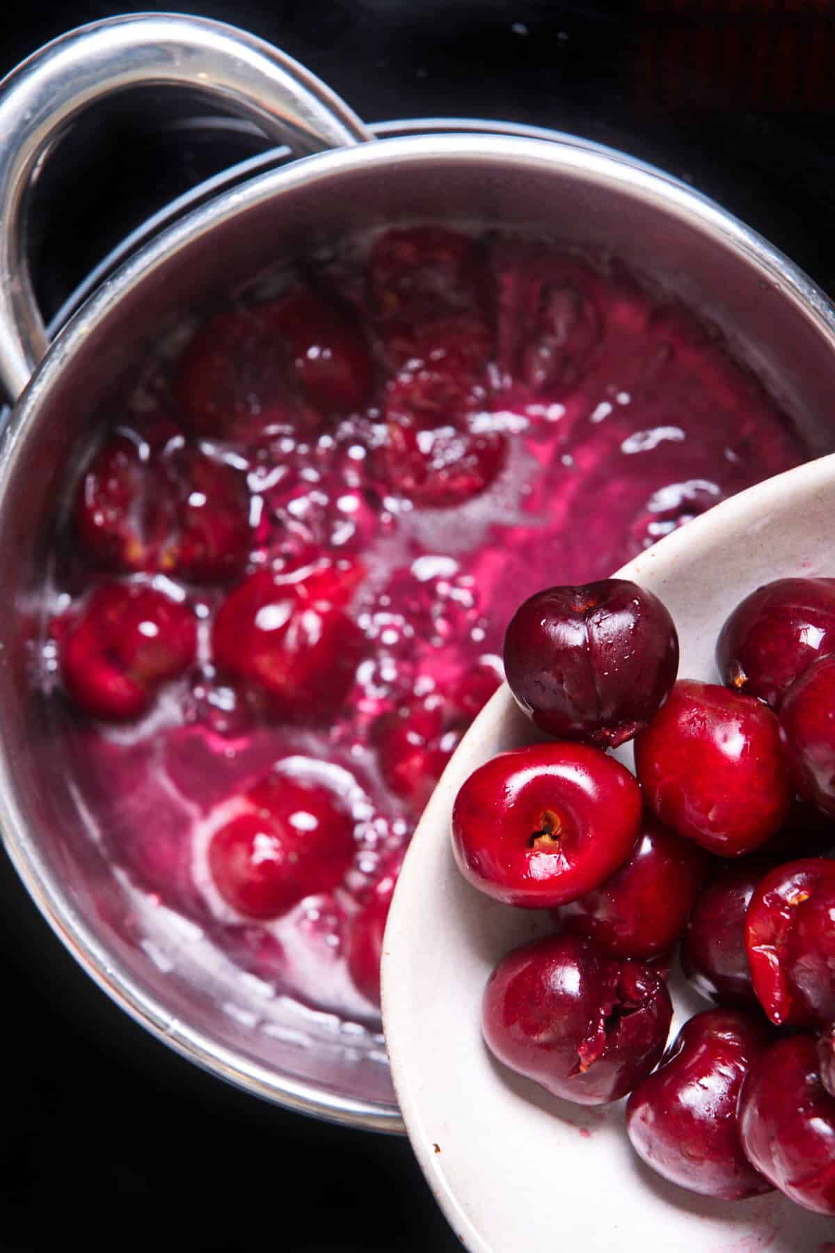 Cherries in a sugar syrup in saucepan.