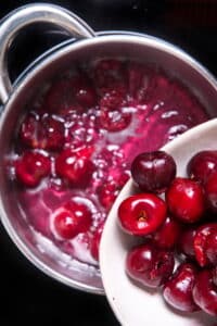 Cherries in a sugar syrup in saucepan.