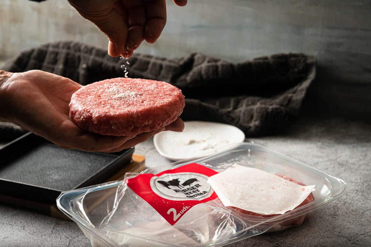 Raw burger patties getting seasoned.