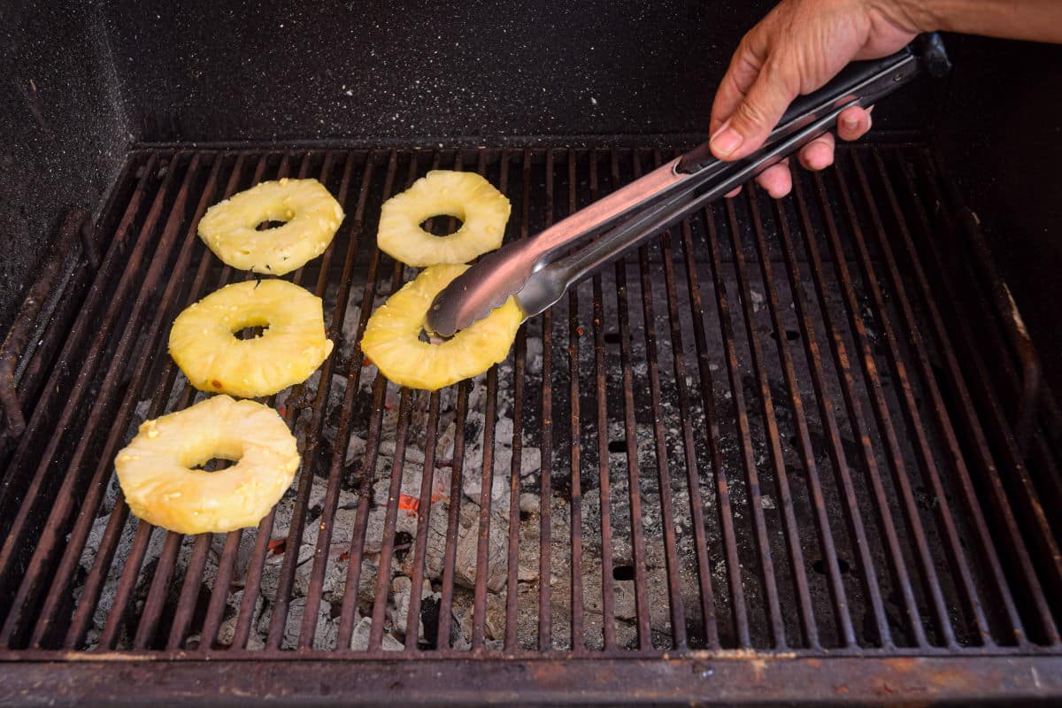 Pineapple slices on an outdoor charcoal grill.