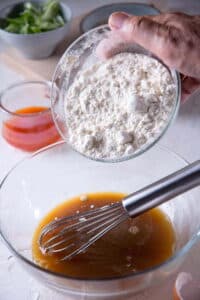 Kimchi batter ingredients in a glass bowl with a whisk.