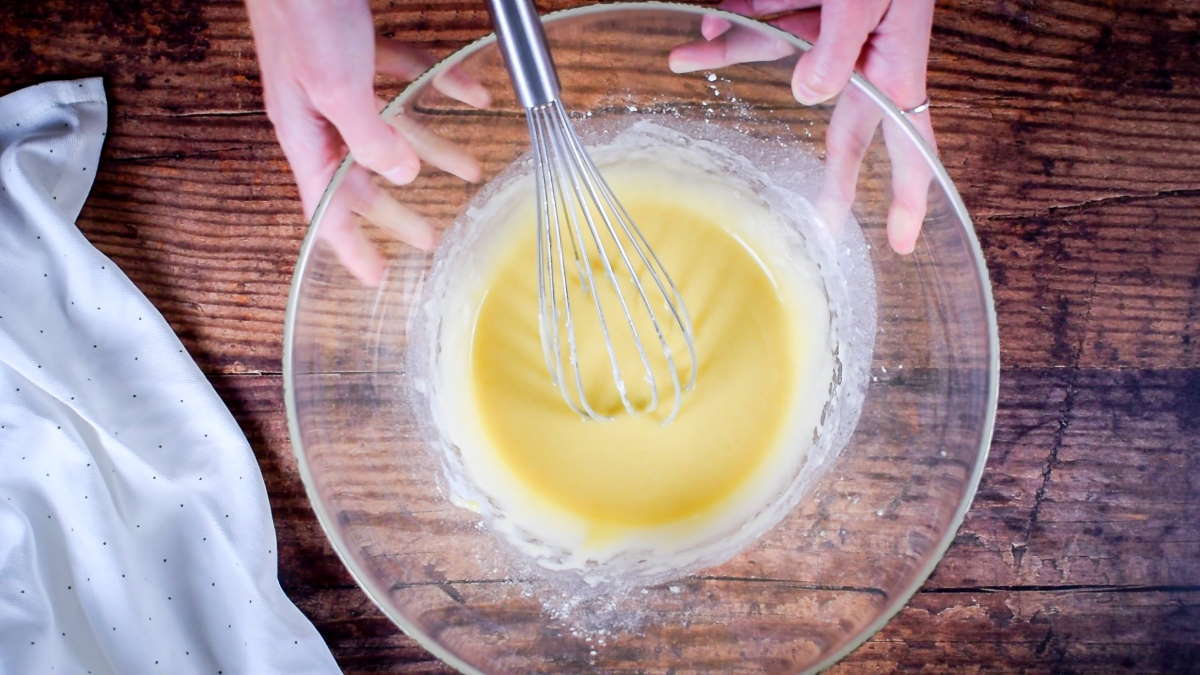 How to Make Cake Pops with a Cake Pop Maker Step 4 Cake batter in a bowl with a whisk. Measuring spoons on the side.