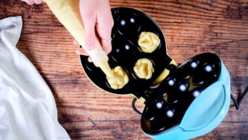 Piping batter into cake pop maker cavities.