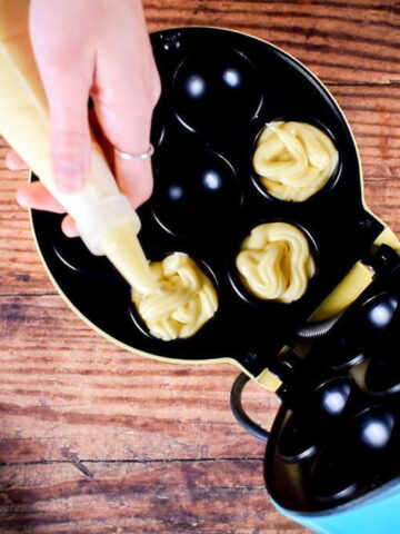Piping batter into cake pop maker cavities.