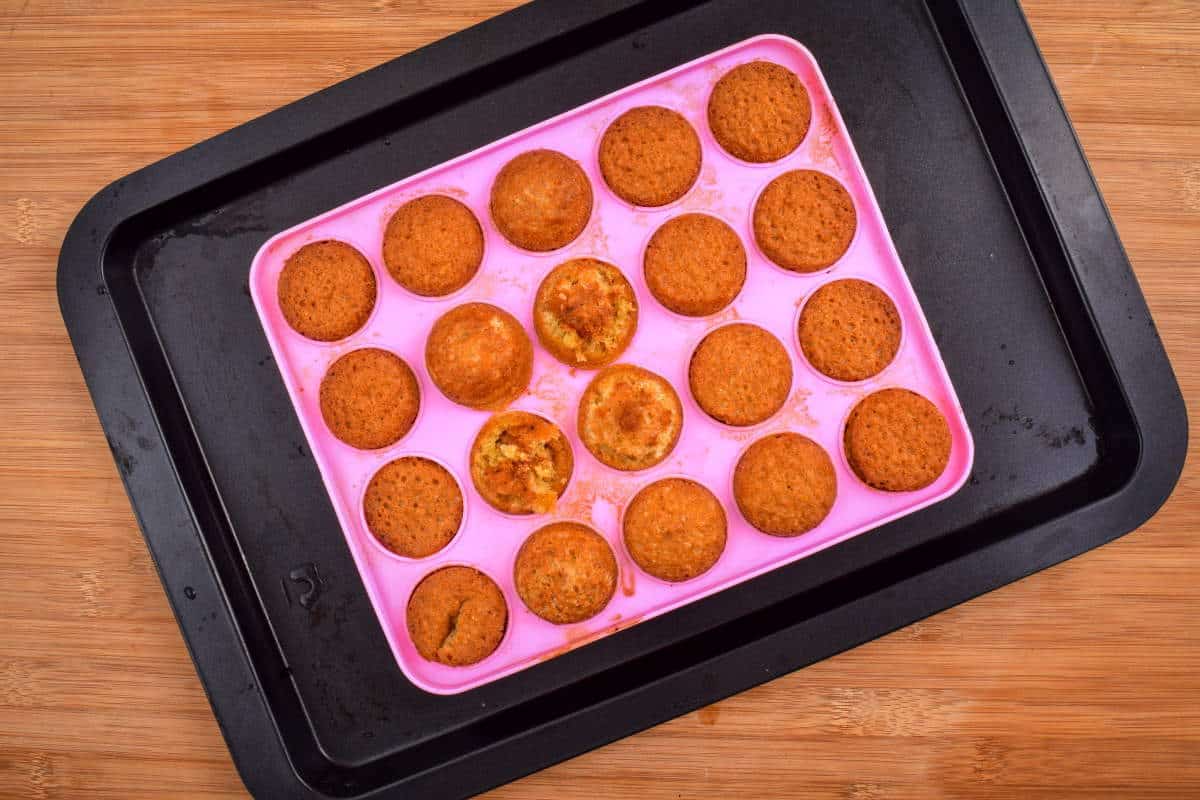 How to Make Cake Pops with a Mold Step 7 Cake balls in a pink cake pop mold on sheet pan, wooden background.