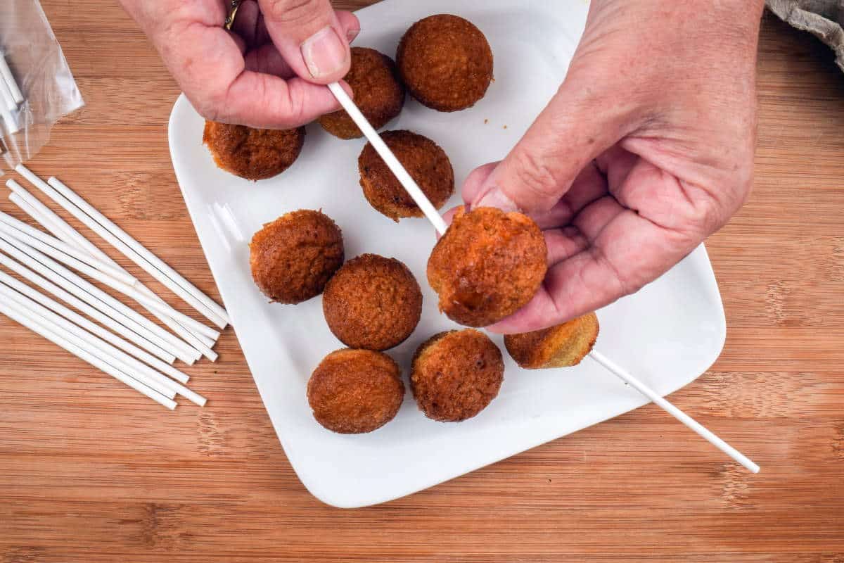 How to Make Cake Pops with a Mold Step 8 Bare cake pops on white plate, wooden background.