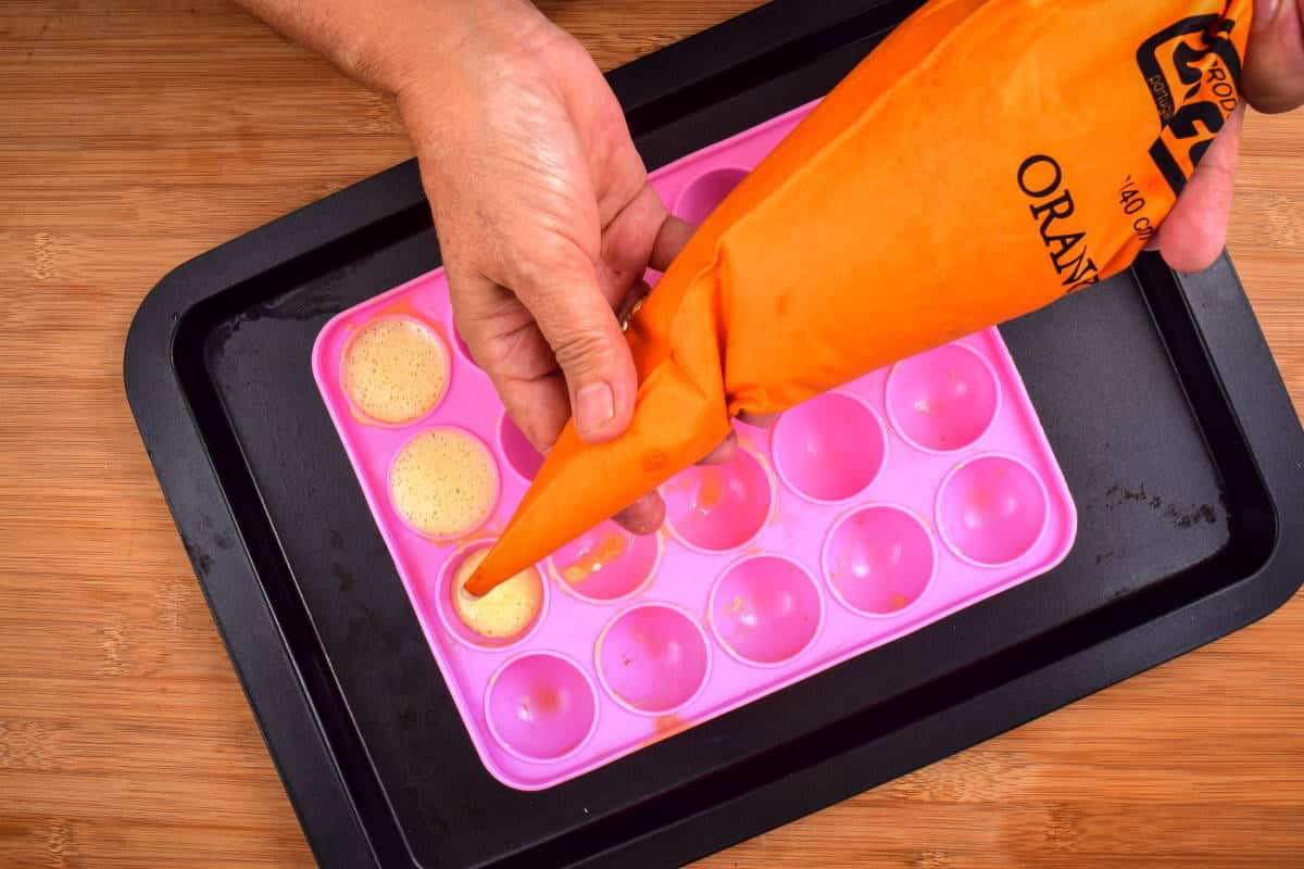 How to Make Cake Pops with a Mold Step 6 Cake pop batter getting piped into cake pop mold with on sheet pan.
