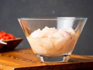 Glass bowl with cubed raw white fish and lemon juice.