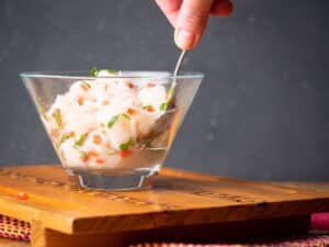 Ceviche in a glass bowl with a spoon.