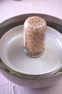 Bowl with a plate and weight on it.