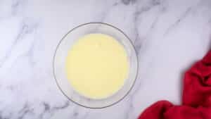 Flour and water mixture in small glass bowl on marble background.