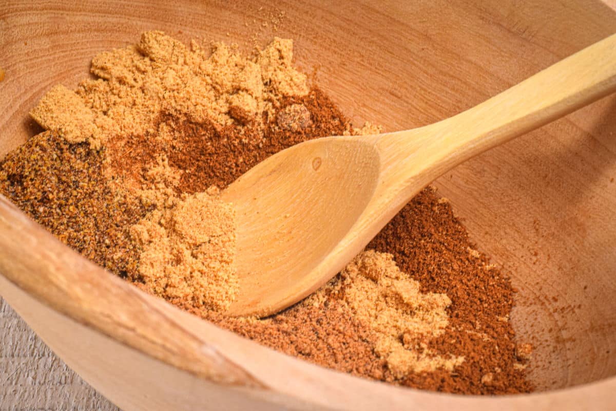 Pumpkin pie spice mix in wooden bowl with wooden spoon.