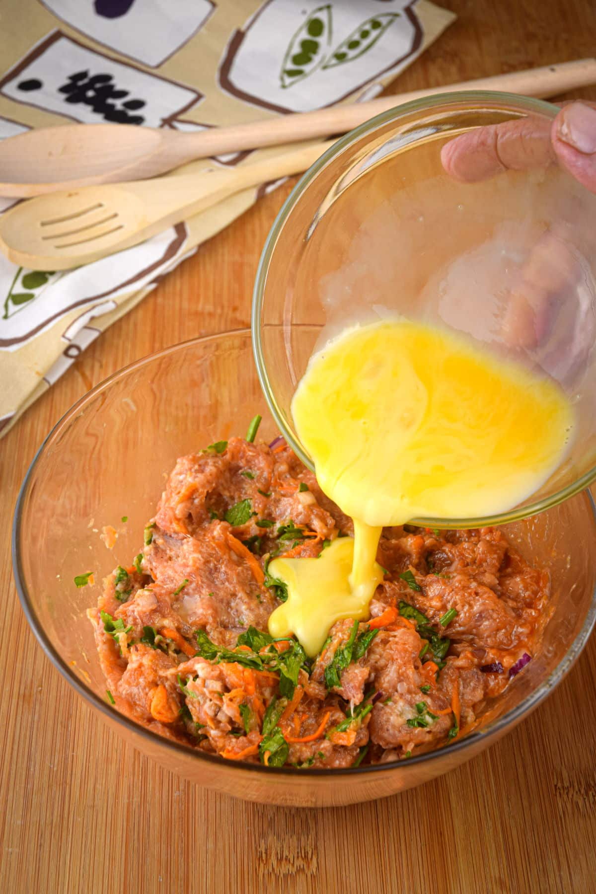 Sausage roll filling in small bowl with beaten egg.