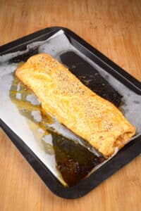 Baked sausage roll on sheet pan.