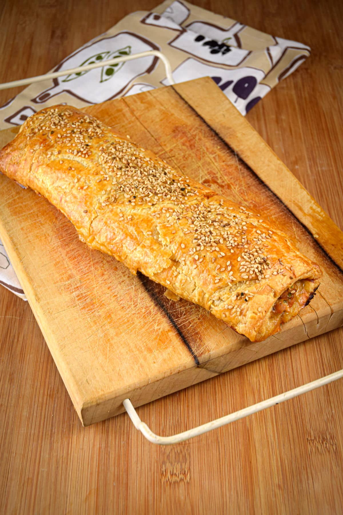 Baked sausage roll on cutting board.