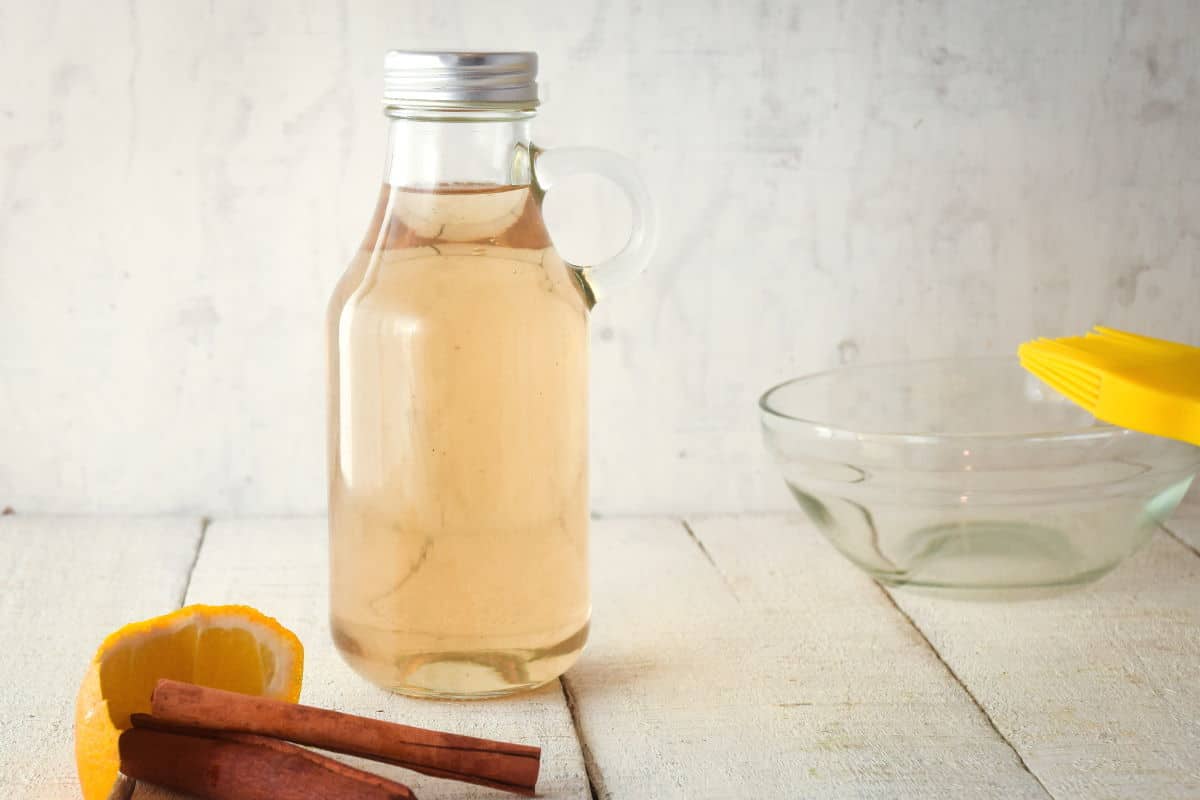 How to Make Simple Syrup Step 5 - Variation 1 A glass bottle of simple syrup, cinnamon and orange on the side.